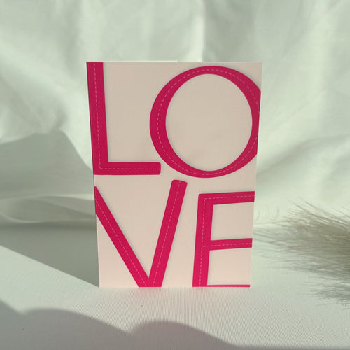 Vaaleanpunainen kortti, jossa LOVE teksti