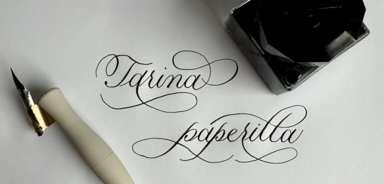 Kalligrafia, kalligrafiakynä ja mustepullo. Kirjoitettu Tarina paperilla.