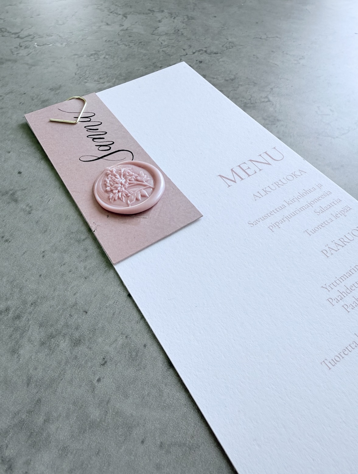 Muut paperituotteet, kuva menusta, jossa teksti vaaleanpunaisella ja paikkakortti kiinnitettynä. Vahasinetti.